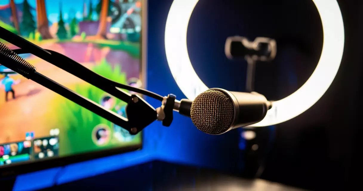 USB streaming microphone on boom arm beside gaming monitor with ring light in background