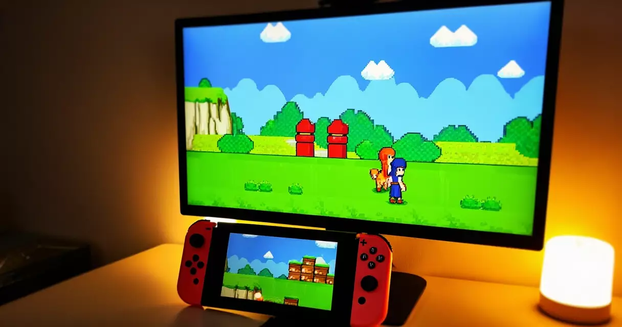 Cozy setup with handheld console and monitor displaying pixel-art indie game visuals