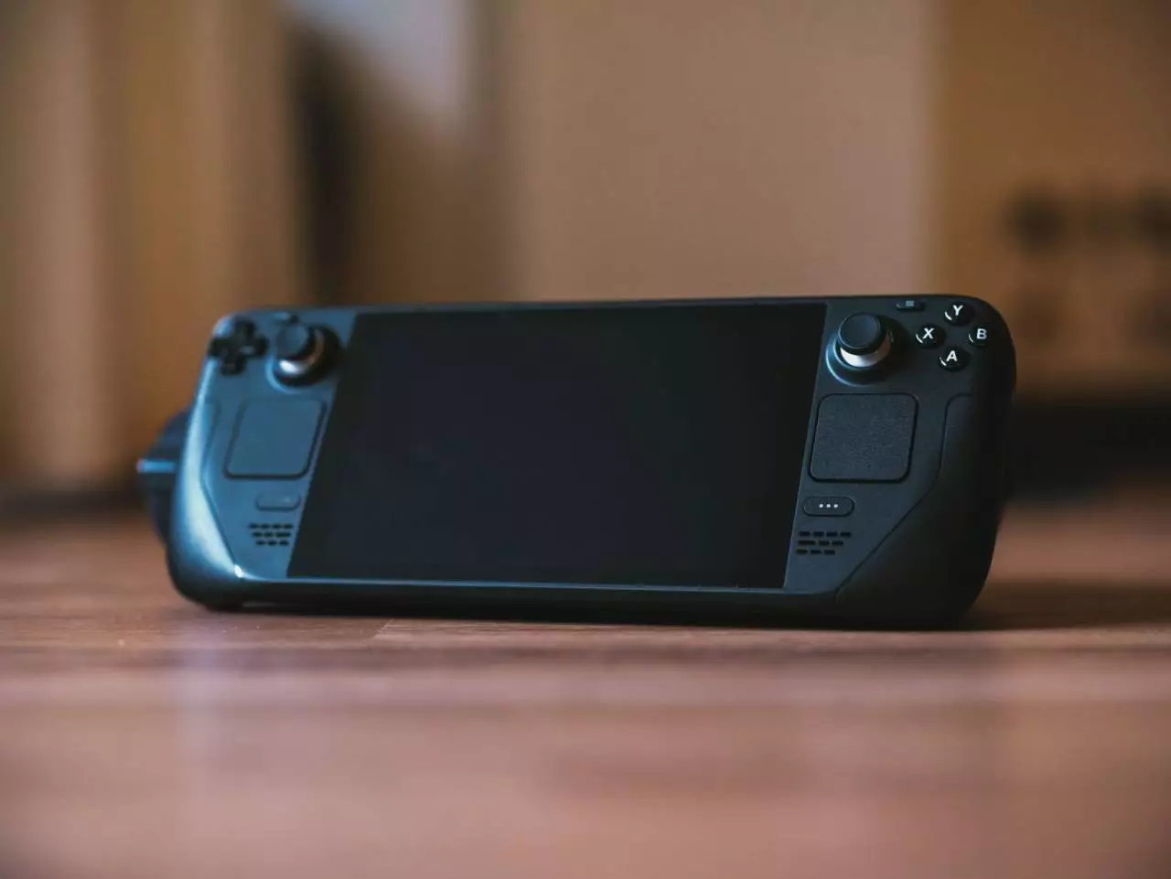 Modern handheld gaming console on a wooden surface representing the Steam Deck OLED portable gaming review for 2026