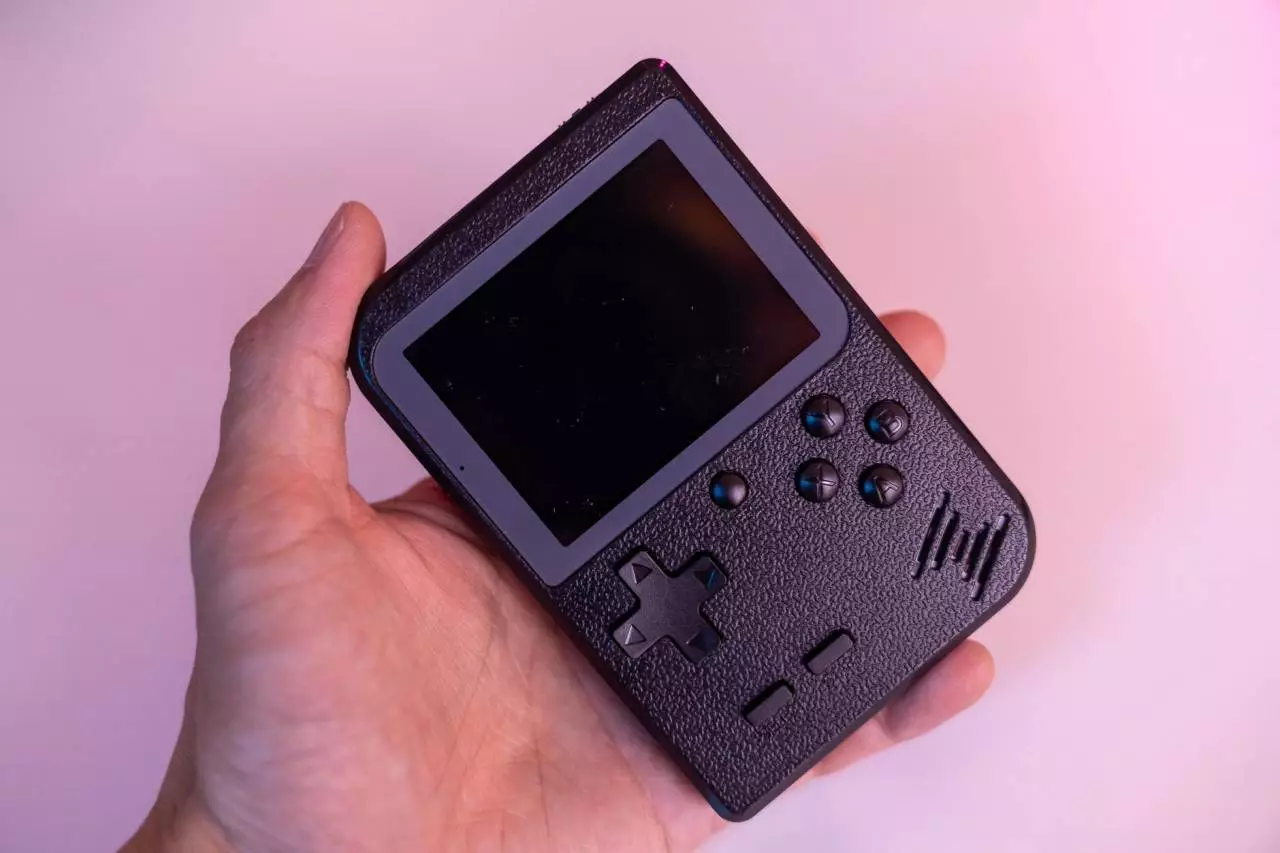 Hand holding a black portable handheld gaming console representing the long-term Steam Deck OLED review and worth it assessment for 2026
